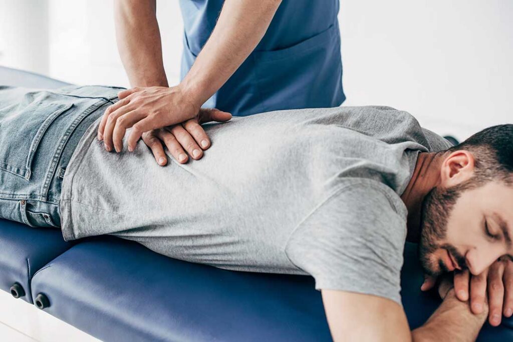 A pregnant person using a pillow for back support while resting on a sofa at home.
